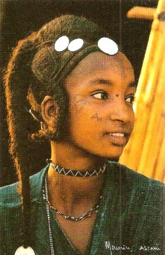 Atnip's Niger Girl with ornate hairstyle and gold coins details and small tightly braided pigtails Niger by Maurice Ascani