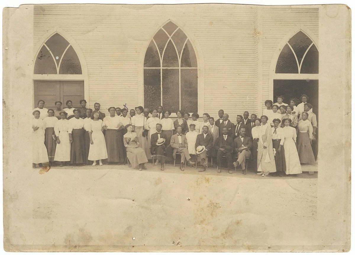 A group of community members in Greenwood posed for a group photograph in front of the Vernon AME Church, Tulsa, OK, 1919. The dress of these individuals speaks to their affluence—the enormity of the church itself an expression of the economic succes