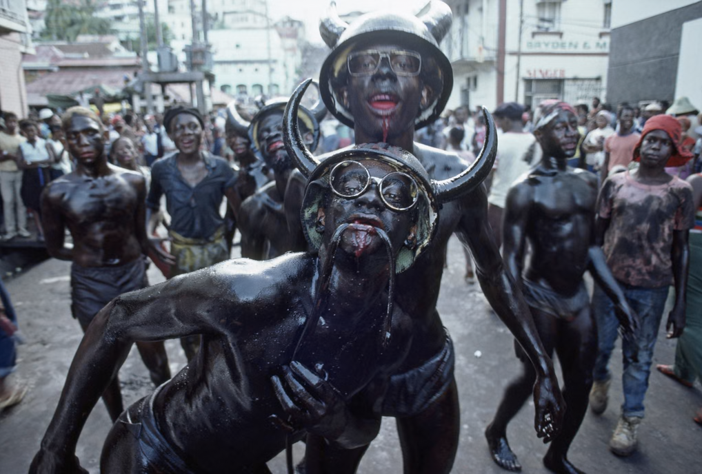 Carnival revellers adorned with dead snakes in Grenada (1984) [Photograph]. In 100 years of photography in the Caribbean in pictures. The Guardian.
