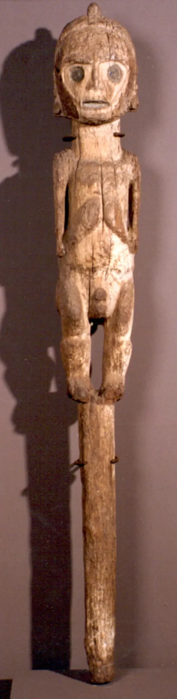 Anthropomorphic Zemi Figure. Taíno culture; Jamaica, Caribbean. Wood, carved.
This full-length anthropomorphic figure represents a zemi — a material embodiment of a spiritual force or ancestral being in Taíno cosmology. The large circular eyes, rigid