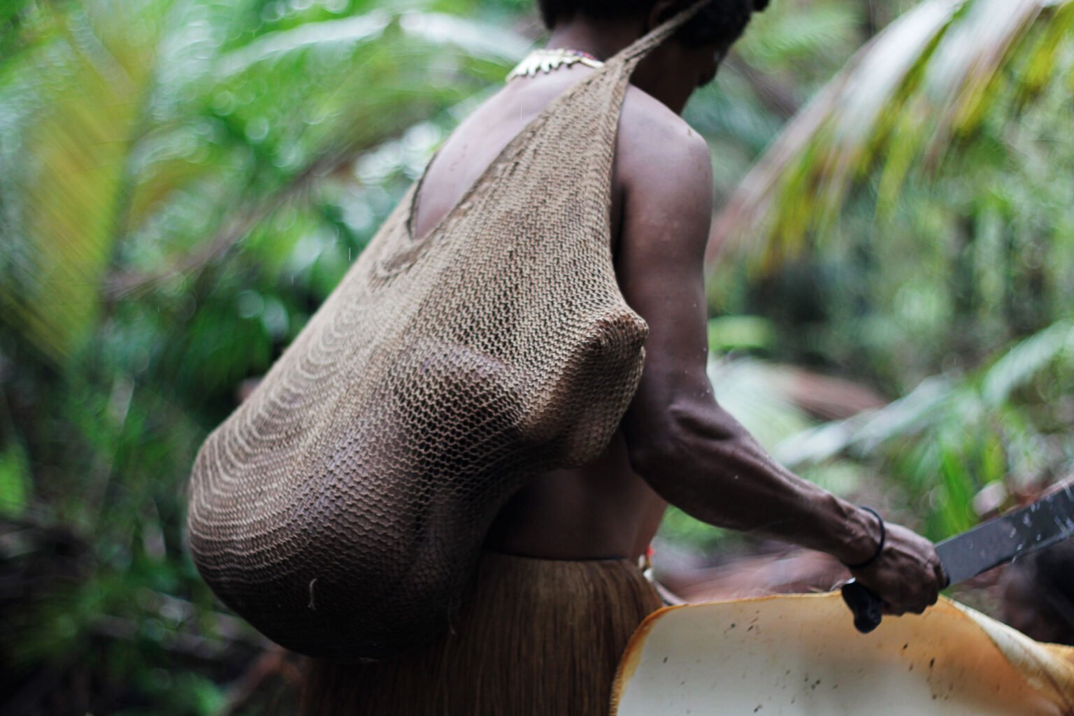 A Korowai woman carries her child in the "noken" carrynet