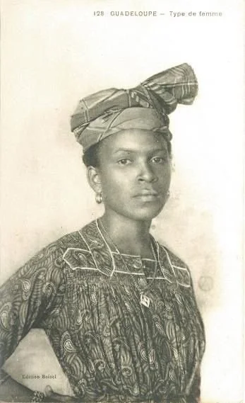 Guadeloupean woman wearing a madras headwrap and patterned Creole dress.