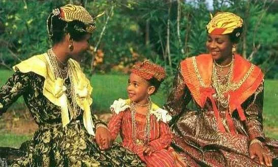 Women and child from the French Caribbean wearing madras headwraps, layered jewelry, and traditional Creole dresses.