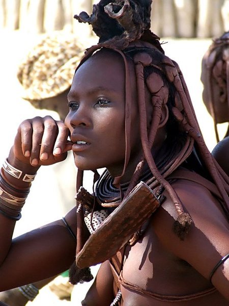 A Himba woman from northwestern Namibia with long, thick braids thickly sculpted with otjize paste. Sourced from Kwekudee.