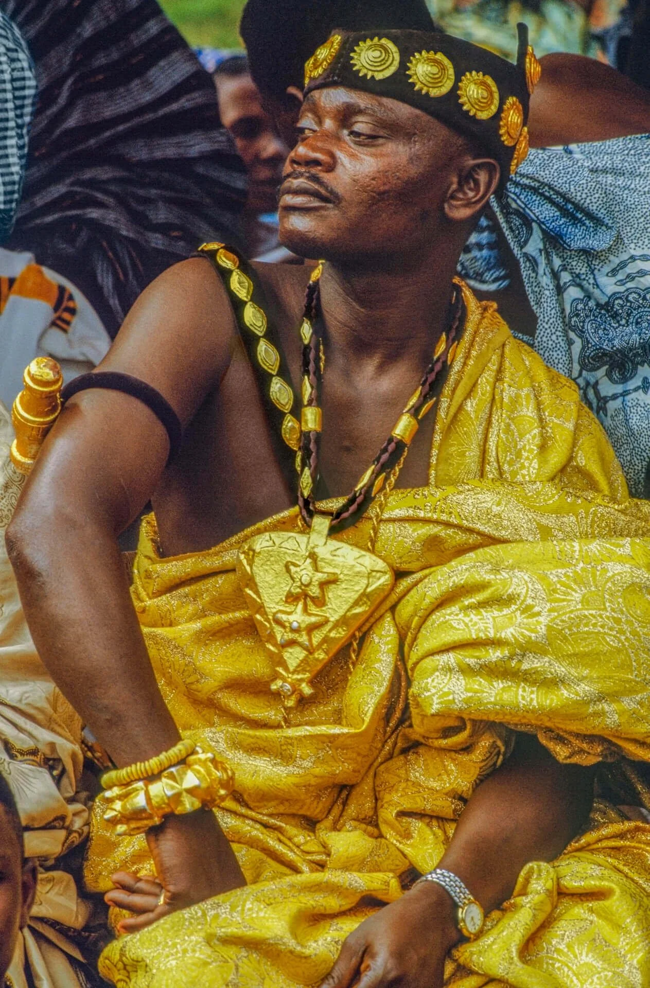 Ashanti Paramount Chief, Ghana.This image portrays an Ashanti paramount chief adorned with a gold medallion and a headband decorated with stylized moon and star motifs. These symbols reference the Akan proverb, “The evening star, desirous of being ma