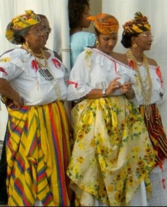 Women from the French Caribbean wearing traditional Creole dress, including madras headwraps, patterned skirts, and layered gold jewelry.