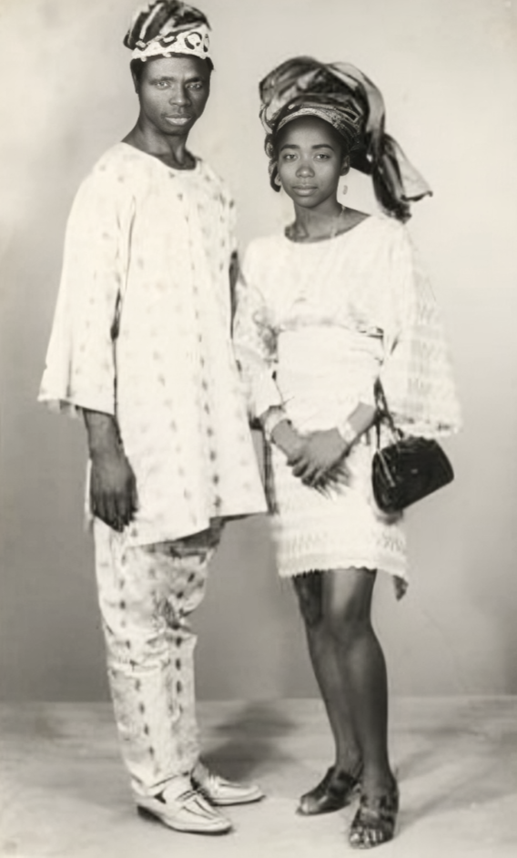 Nigerian couple wearing an Agbada and a lace dress, photographed by Paramount Photography Studios circa 1970s. 