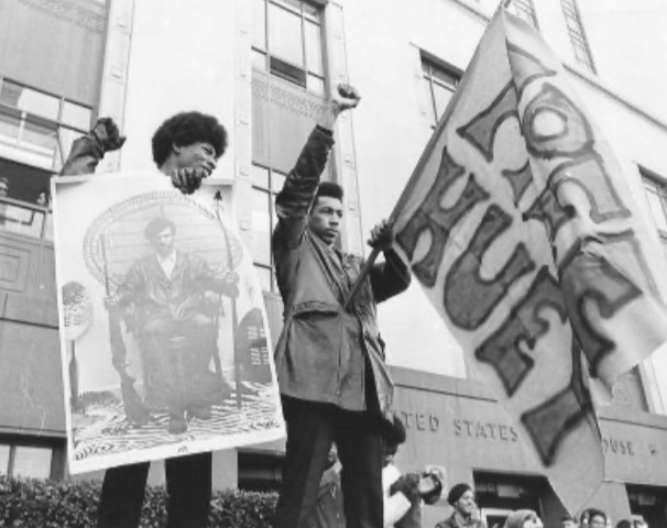 Photograph of Black Panther Party members holding a “Free Huey” flag and raising their fists during a protest demonstration. Photographer unknown, c. late 1960s.