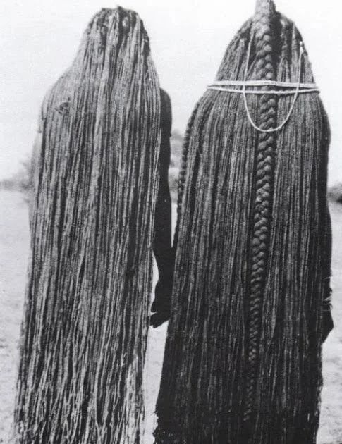Two women from the Mbalantu of Wambo group, with ankle-length braids through the use of sinew (eefipa) extensions. Photographed by M. Schettler, circa 1940s.