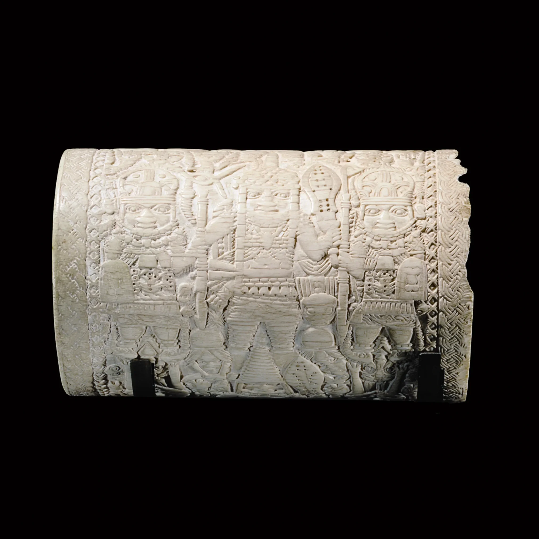 An ivory arm cuff made in Benin Nigeria, covered with champlevé motifs, revealing four rows of standing figures and two repeating war scenes arranged alternately. 