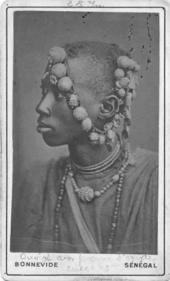 A Fulani man from Senegal wearing his mothers granulated metal spheres and multiple beads in his hair as he undergoes an initiation rite.