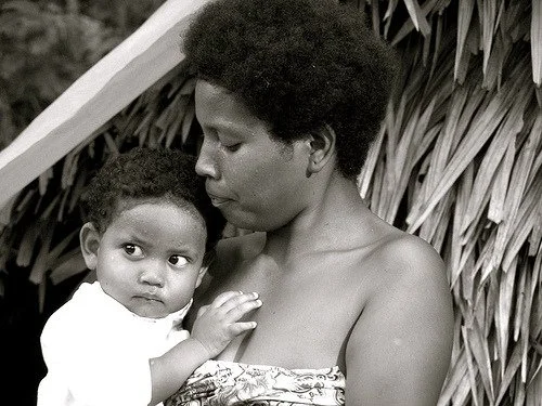 Portait of a Maniq woman holding a baby  — Image via Diasporic Roots
