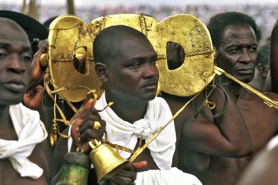 An Attendant carrying Sikadwa Kofi in a procession. Unknown photographer. (n.d.). An attendant carrying Sikadwa Kofi in a procession [Photograph]. Earth Metropolis. https://www.earthmetropolis.com/Earth/ashanti_kings.html