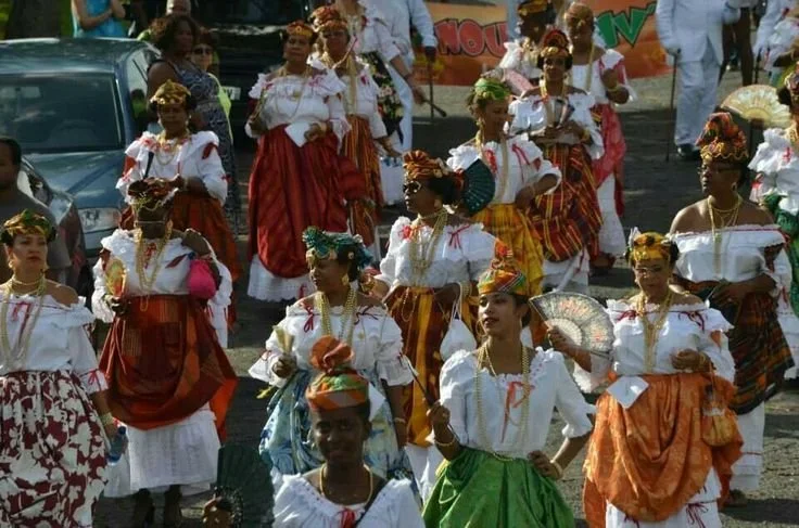 Women from the French Caribbean wearing madras headwraps and traditional Creole dresses, participating in a cultural procession associated with Antillean festivals and community celebrations.