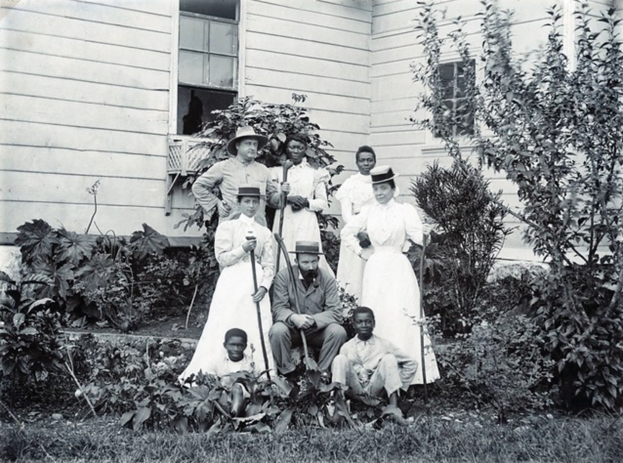 Caribbean Photo Archive. (n.d.). [Group portrait in a garden outside a wooden house] [Photograph]. Flickr. https://www.flickr.com/photos/caribbeanphotoarchive/with/49059240108
