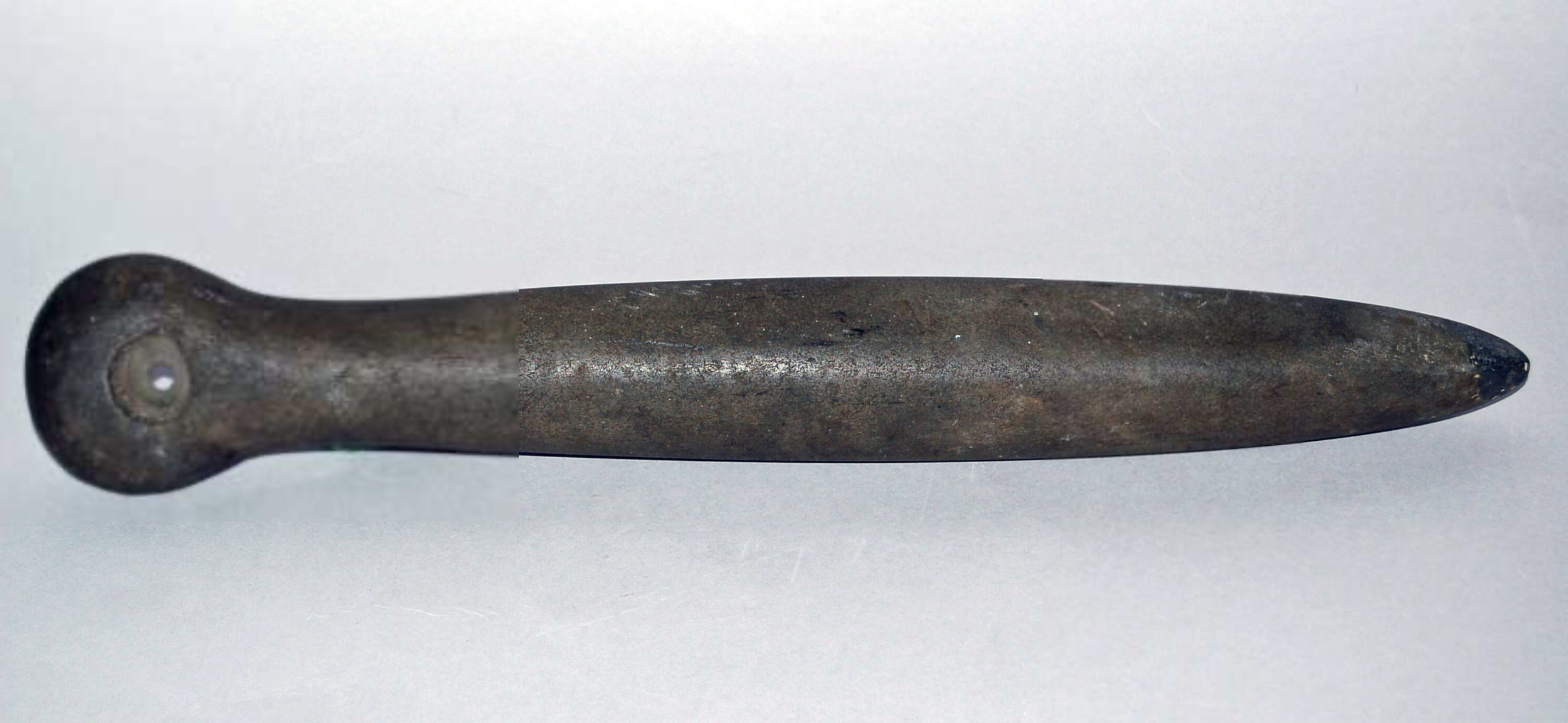 Stone Club (Possibly Ceremonial). Stone; Length 45.50 cm × Width 7 cm × Depth 5.10 cm. Caribbean, Americas. This carved stone club features a pointed distal end, a broadly lenticular shaft, and a discoidal proximal end with a central perforation. Its