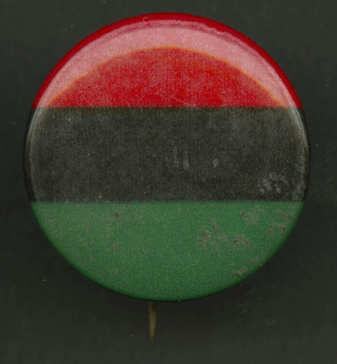 Manufactured by AFL-CIO, American, founded 1955, and Owned by Jan Bailey, American, 1942 - 2010. Pinback Button of the Pan-African Flag. after 1955. Metal, Diameter: 1 × 1/4 in. (2.5 × 0.6 cm). National Museum of African American History and Culture;