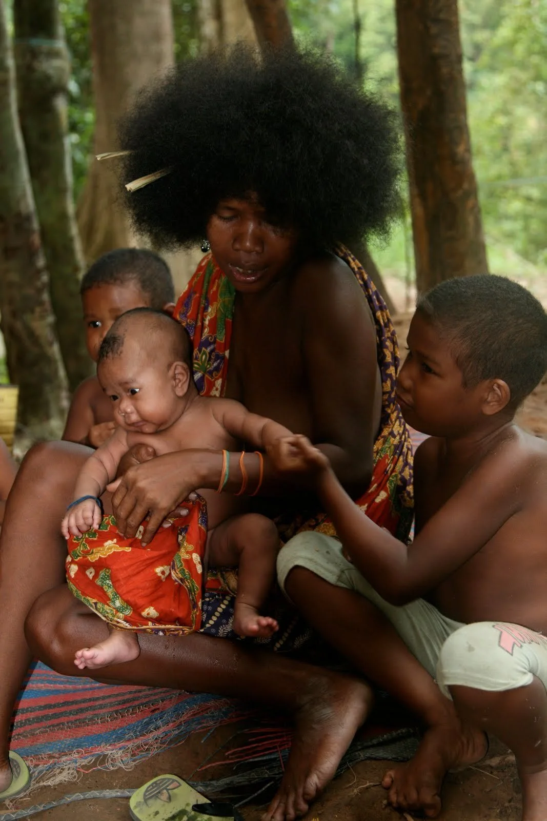 Portait of a Maniq woman holding a baby alongside children — Image via Diasporic Roots
