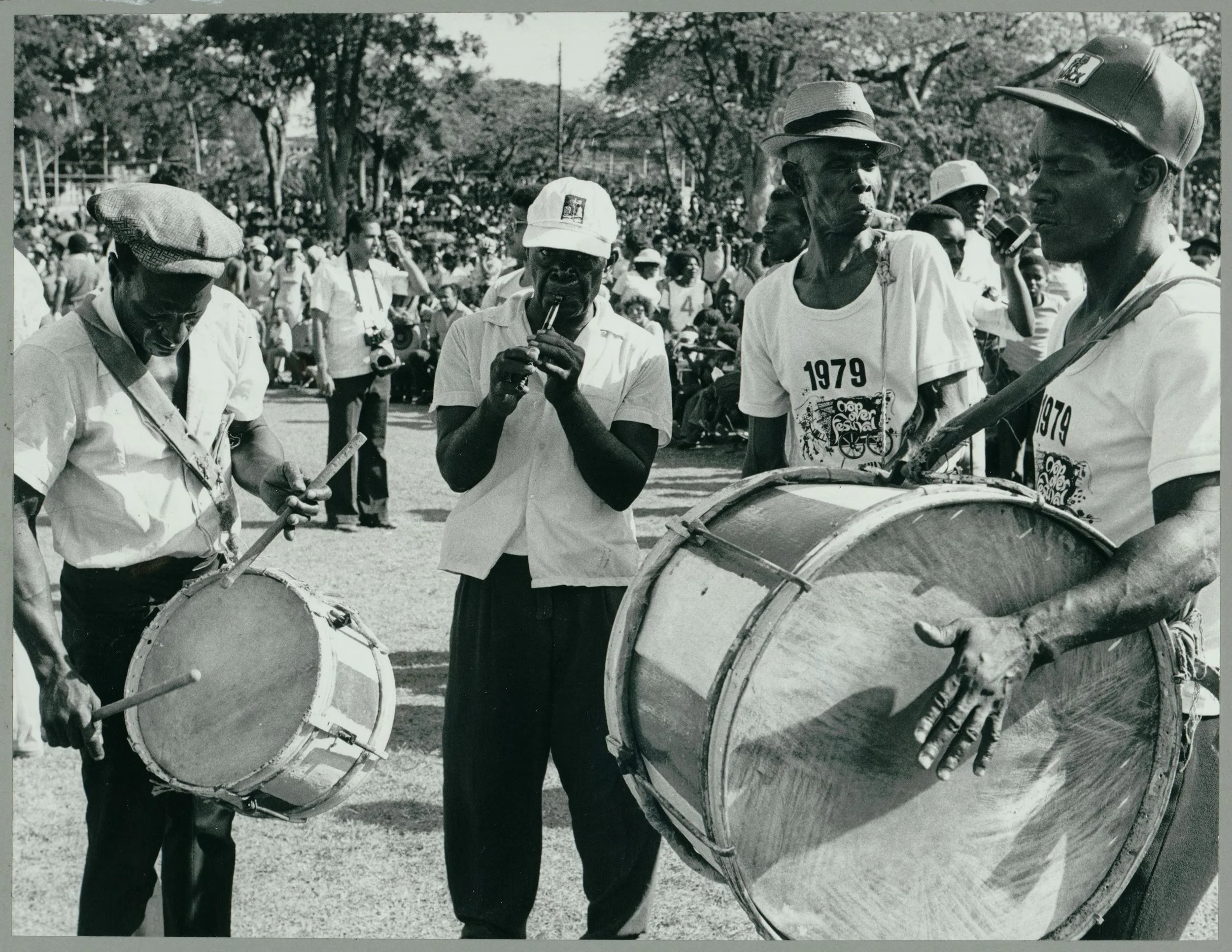 Traditional Bajan Music. "This photograph shows drummers and flute players in a local band playing traditional folk music in a parade in Barbados, with a large crowd in the background. The parade is part of the five-week summer Crop Over festival, th