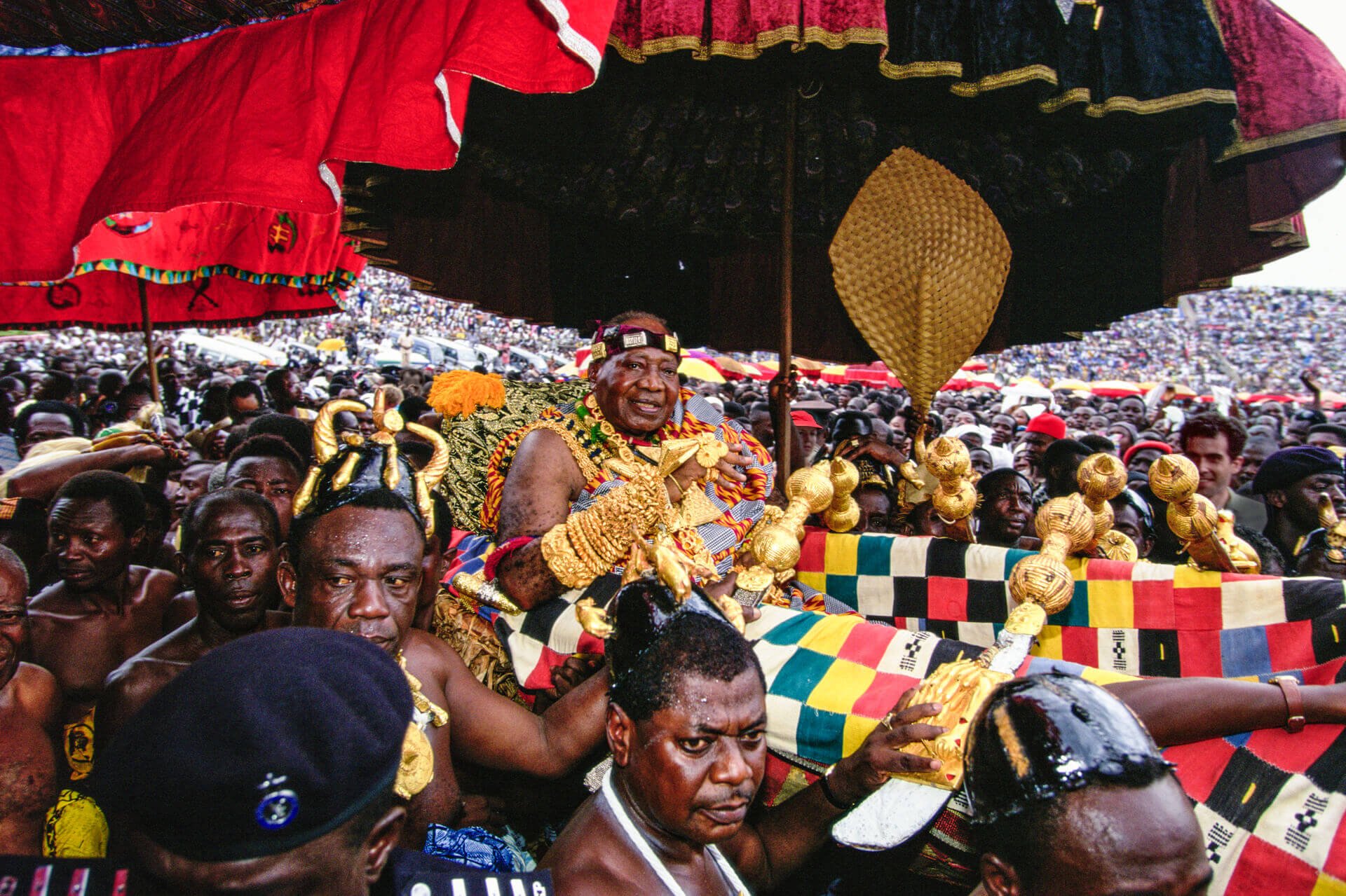 The Asantehene (King) Otumfuo Opoku Ware II carried in palanquin at Silver Jubilee, Ghana. Unknown photographer. (n.d.). The Asantehene (King) Otumfuo Opoku Ware II carried in palanquin at Silver Jubilee, Ghana [Photograph]. Africa Online Museum. htt