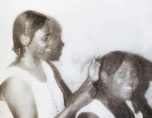 Saeda Kamaal is attended by her hair plaiter in 1960s-70s Omdurman.