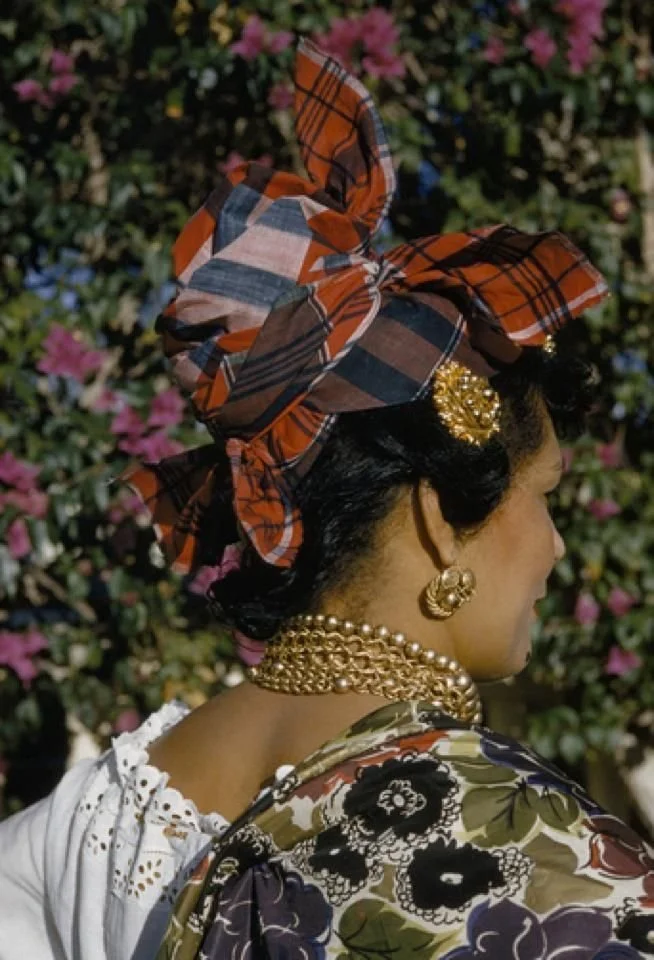 Woman from the French Caribbean wearing a madras headwrap, layered gold jewelry.