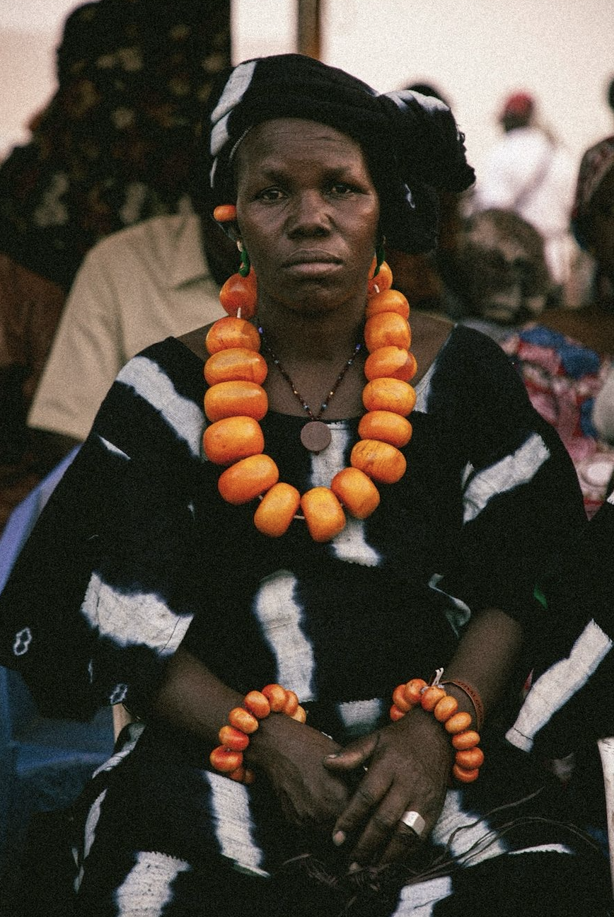 A Dogon woman wearing a patterned indigo cloth and large amber beaded jewelry.