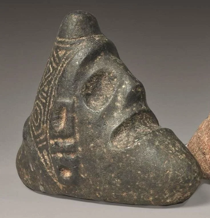A Taino Zemi Trigonolith (zemi, trigonolite) made of basalt. 15.5 cm (6.1 in). Dated CA. A.D. 800-1500. Originates from the Greater Antilles. Categorized as cephalomorphic and belongs to the Taino culture.
