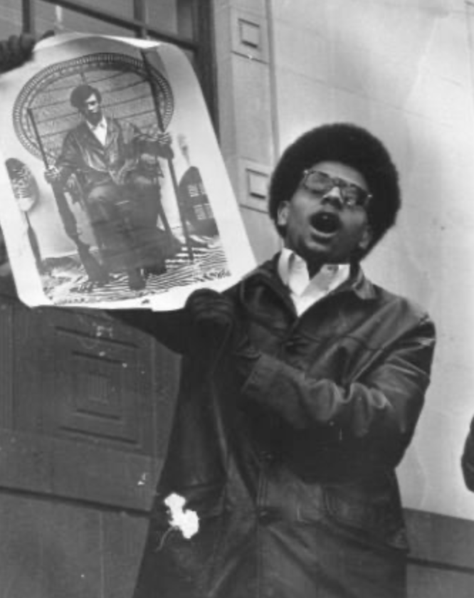 Photograph of a Black Panther Party member holding a poster of Huey P. Newton during a protest demonstration. Photographer unknown, c. late 1960s. Aaron Dixon Collection, Seattle Civil Rights & History Project.