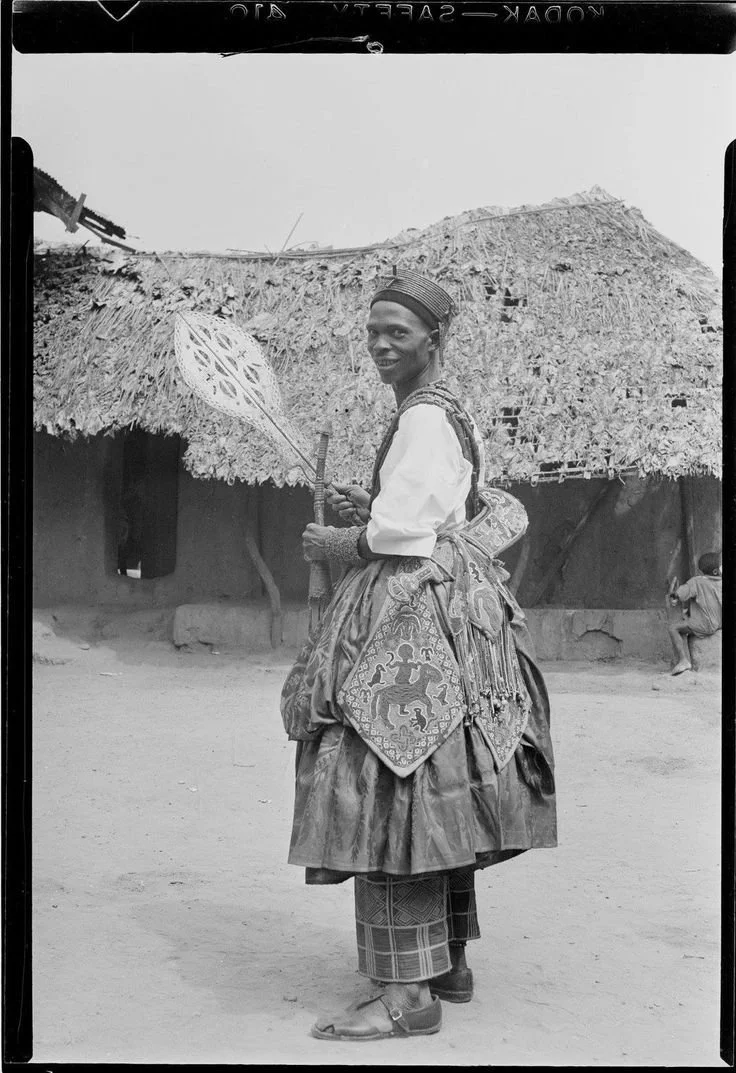 Chief Ariyo holds an ape and an iyaṣin omalóre in his hands while wearing an udamalore and eja at his hip. Photo: Justine Cordwell, 1949, courtesy of Colin Cordwell.