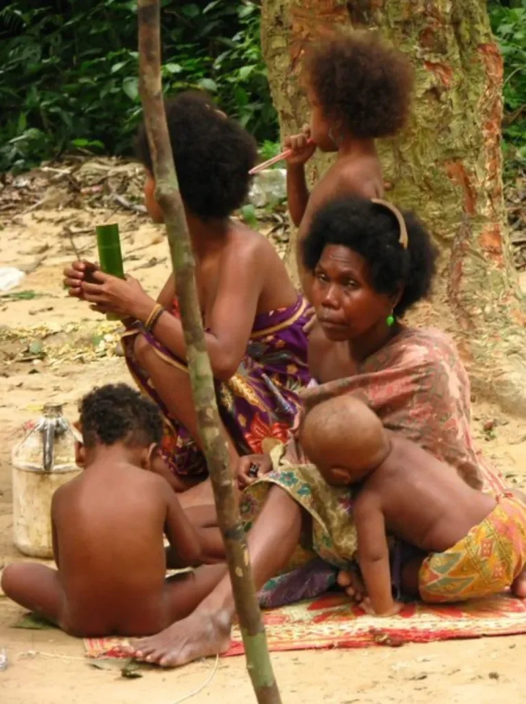A group of Maniq people sitting down alongside children — Image via Livity.Blog