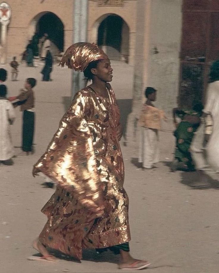 Malian woman wearing a golden boubou and headwrap.