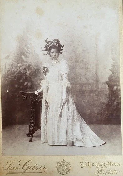 Right: Queen Ranavalona III circa 1900 in Algeria wearing European high fashion and exotic headdress, the dress bearing Madagascar flowers. Kerry Taylor Auctions