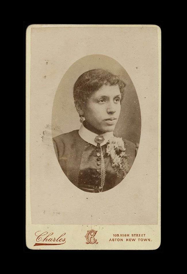 Oval vignette portrait of a young woman wearing a high-collared dress with floral adornment.  Photographed by Charles, Aston New Town, Birmingham, England , circa 1880s.