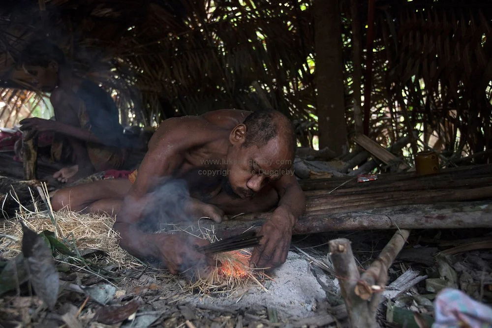 Portrait Champ, a Maniq tribe member, preparing a small fire to heat his poison darts on — Image via Luke Duggleby