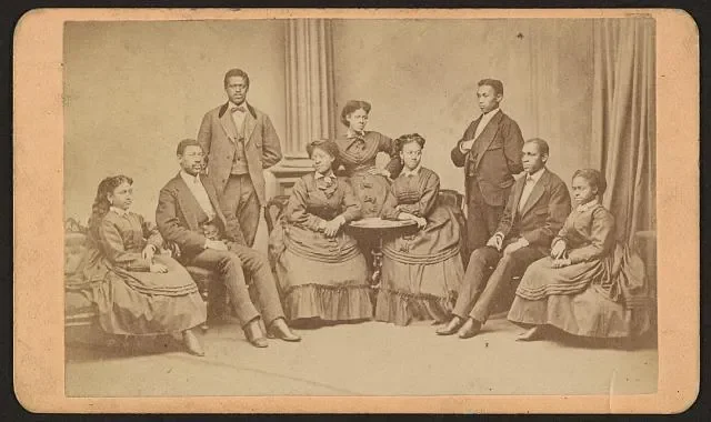 A studio group portrait of the Fisk University Jubilee singers. From left to right: Minnie Tate, Greene Evans, Isaac Dickerson, Jennie Jackson, Maggie Porter, Ella Sheppard, Thomas Rutling, Benjamin Holmes, and Eliza Walker. James Wallace Black / Ame