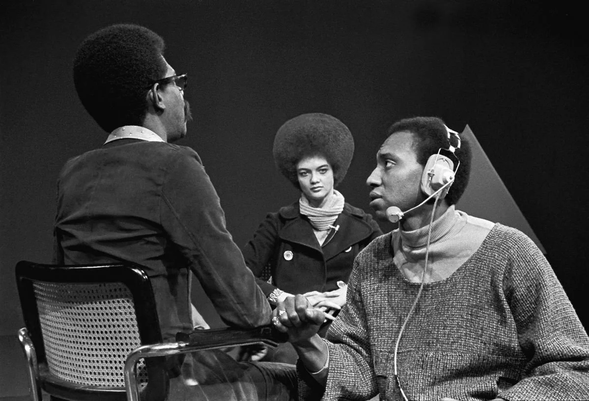 Soul! host Ellis Haizlip takes a break from interviewing Kathleen Cleaver of the Black Panthers while a sound engineer checks the mic. Photo by Chester Higgins Jr. 