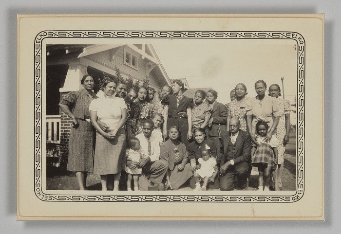 The Princetta R. Newman Collection of Family Photographs, Tulsa, Oklahoma. (n.d.). Photographic print of a large group of people posing outside of a house, mid 20th century. Collection of the Smithsonian National Museum of African American History an