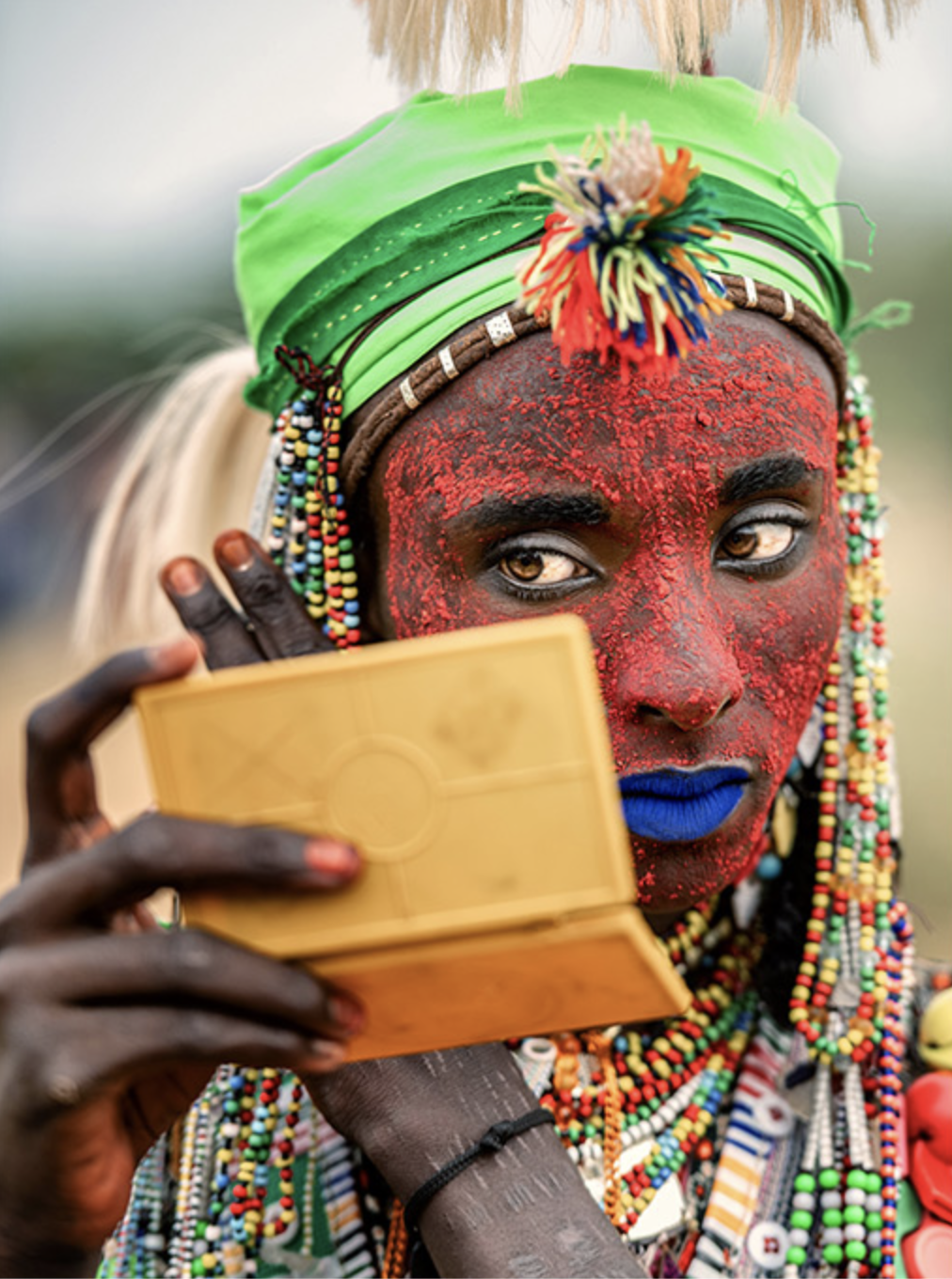 A Djapto man adorning himself with a small mirror — Source: Eye Tpoty