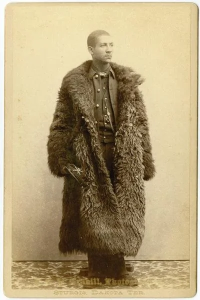 Soldiers of the 25th Infantry wore buffalo robes to protect themselves from sub-zero temperatures. They were charged with routing out white ranchers illegally selling goods to Native Americans. Credit: 25th Infantry soldier wearing a buffalo robe, ph