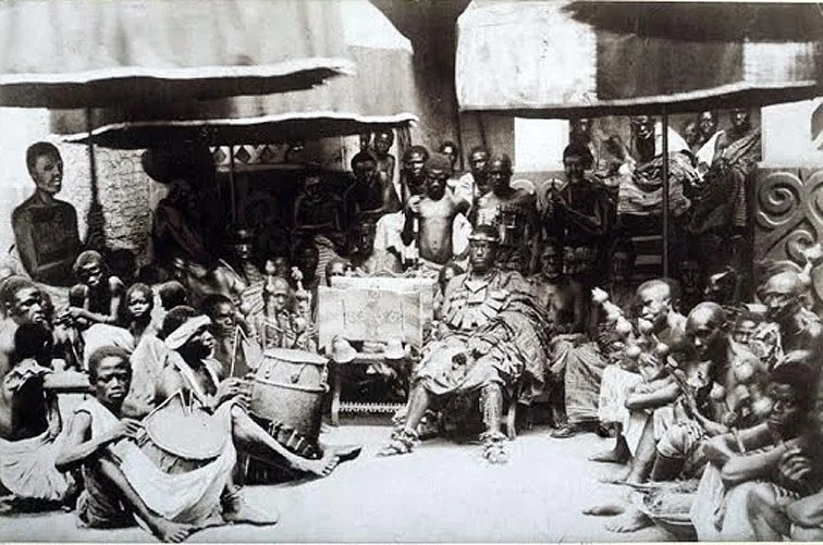 “King Kwaku Dua & Golden Stool in Kumasi with attendants” (c. 1880, attribution uncertain). This historical photograph is traditionally identified as depicting an Asantehene (Ashanti king), often attributed to King Kwaku Dua, seated among attendants 