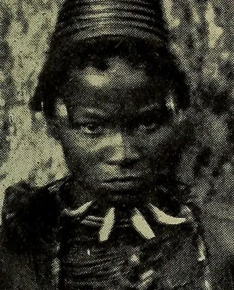 An Igbo woman wearing a necklace made of leopard's teeth mixed with aggry beads. These necklaces were strictly reserved for chiefs, nobility, and their prospective brides. They served as a direct visual marker of wealth, high social standing, and pol
