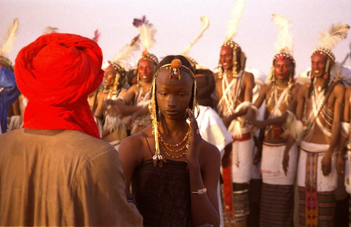 A young Wodaabe maiden coyly judges the contestants at the Gerewol festival. Photographed 1997 in Niger