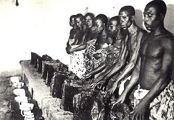 Ashanti ritual attendants performing purification rites, Ghana. This image shows a group of Ashanti ritual attendants gathered around sacred stools, engaging in a ceremonial act of washing or purification. In Ashanti culture, stools are not merely ob