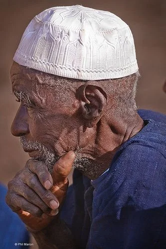 A Dogon man in a white embroidered cap and traditional indigo garment.