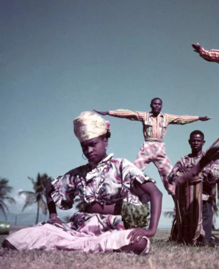 Haitian dancers performing in traditional madras headwraps and patterned Caribbean dress.