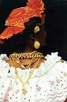 Woman from the French Caribbean wearing a madras headwrap, layered gold jewelry.