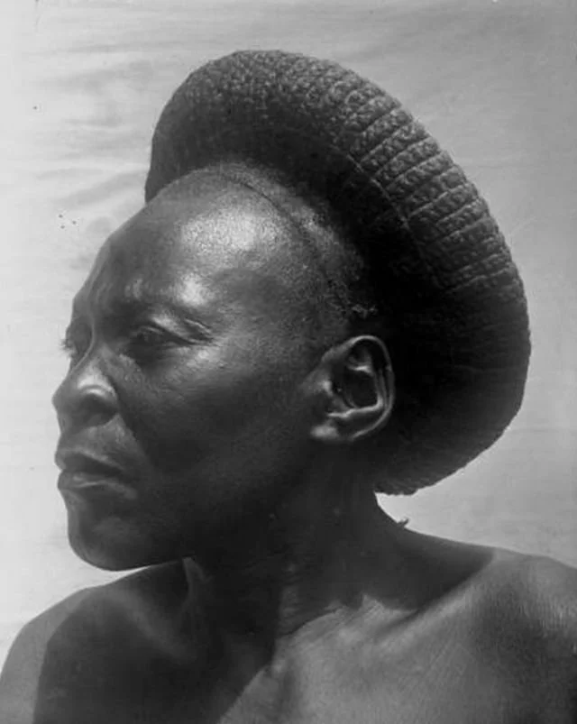 A basket-woven halo hairstyle worn by a woman from Foumban, Cameroon circa 1911 to 1915. Sourced from Vintag.es.