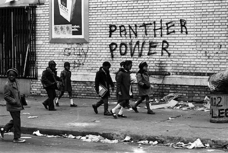 Children walk by Panther Power graffiti photographed by Stephen Shames