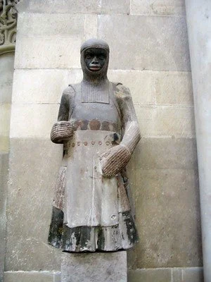In the Magdeburg Cathedral is the oldest known image depicting Saint Maurice as a Moor ( = Mauritius). The statue is carved around 1250 and shows him as an armoured knight.
St.Maurice was a leader of the Theban Legion. Tradition tells, that the comp